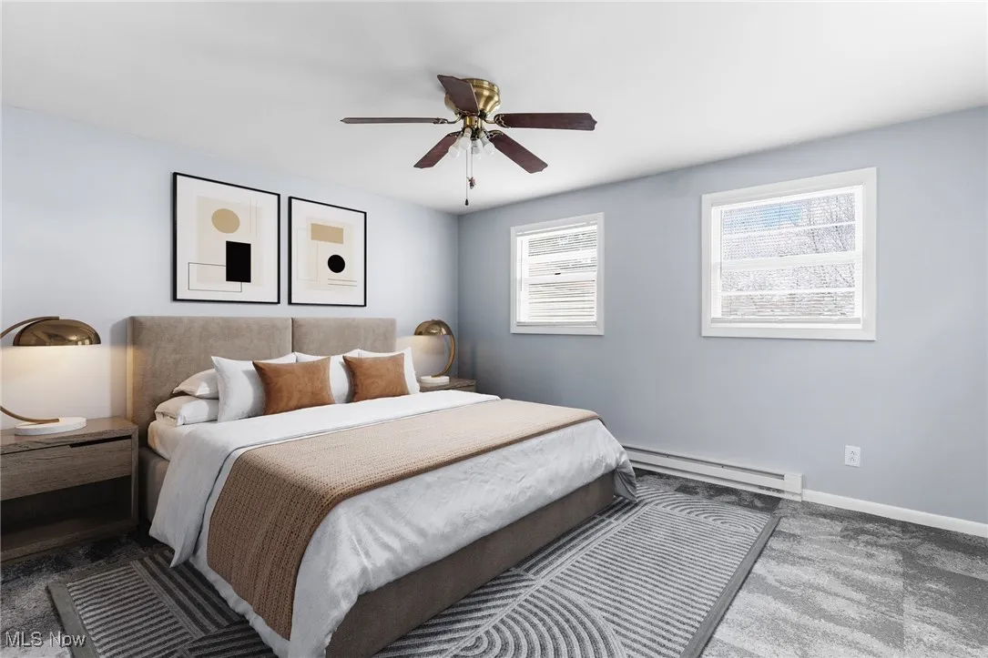 Carpeted bedroom with baseboards, a ceiling fan, and baseboard heating