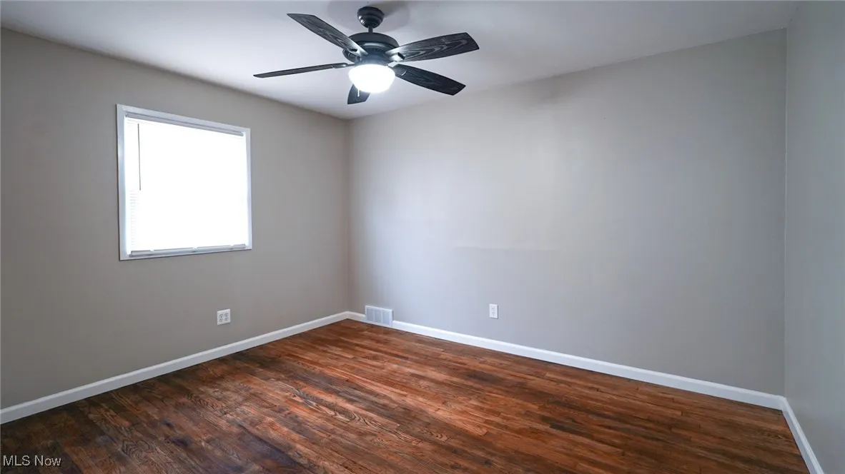 Spare room featuring dark wood-type flooring and a ceiling fan