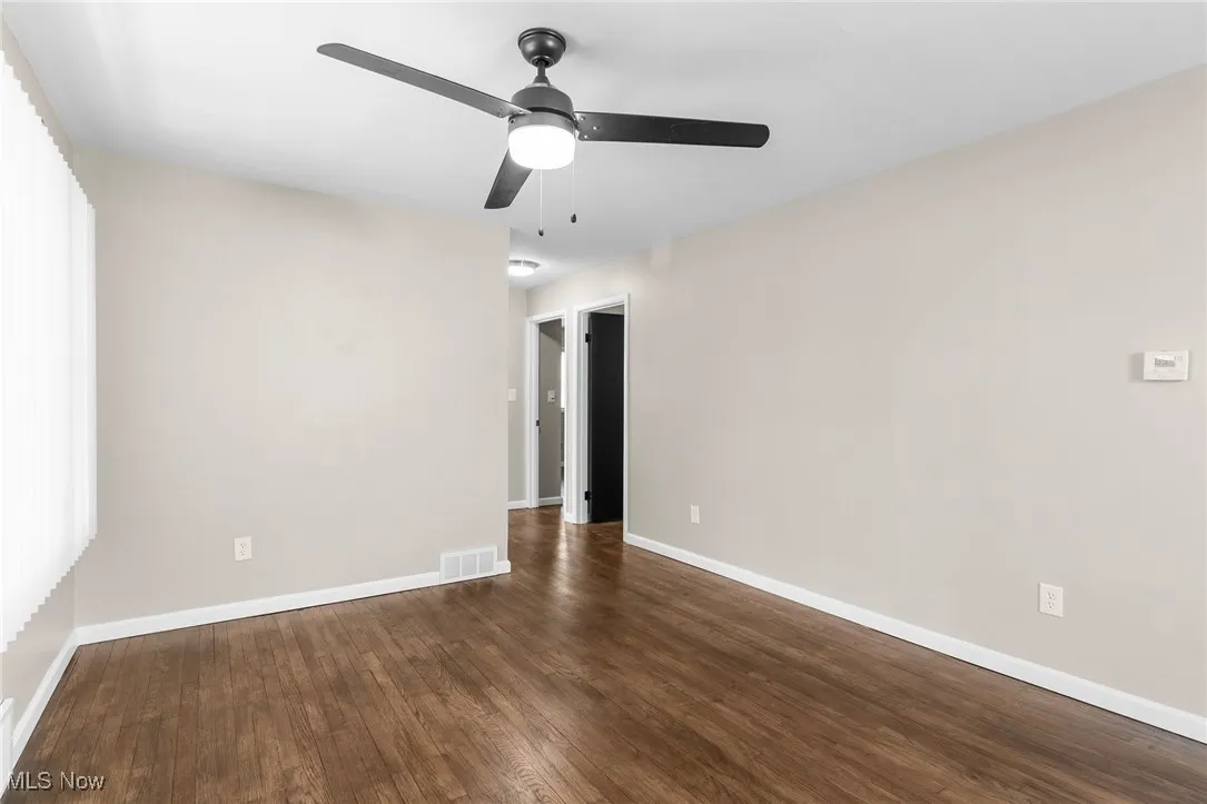 Unfurnished room featuring baseboards, visible vents, wood finished floors, and ceiling fan