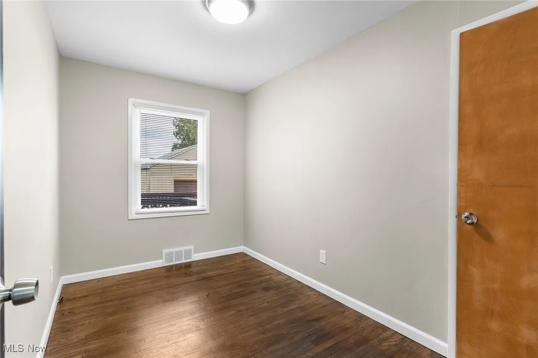 Unfurnished room with dark wood finished floors, baseboards, and visible vents