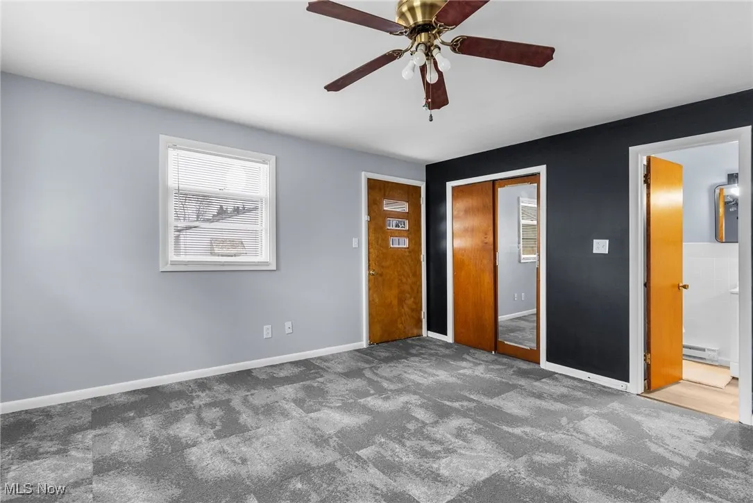 Unfurnished bedroom featuring a closet, baseboards, a ceiling fan, a baseboard heating unit, and carpet floors