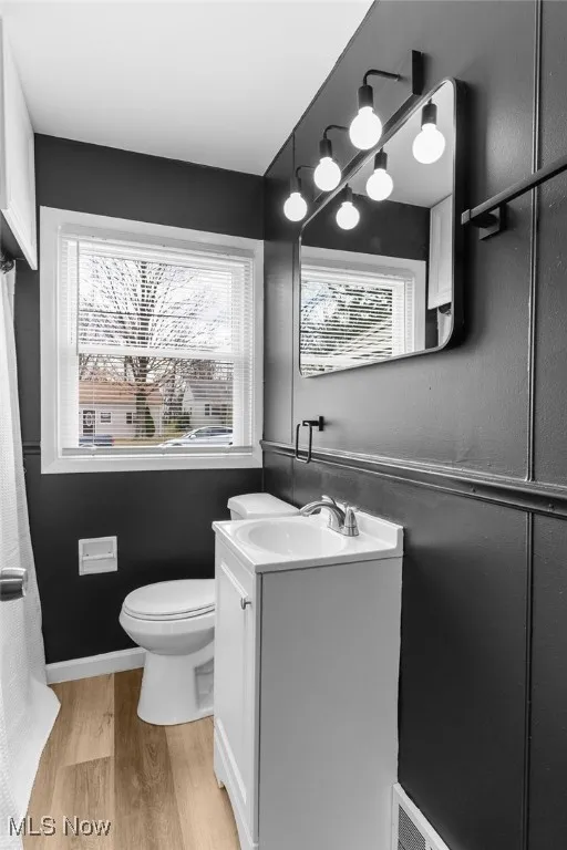 Full bathroom featuring baseboards, wood finished floors, toilet, and vanity