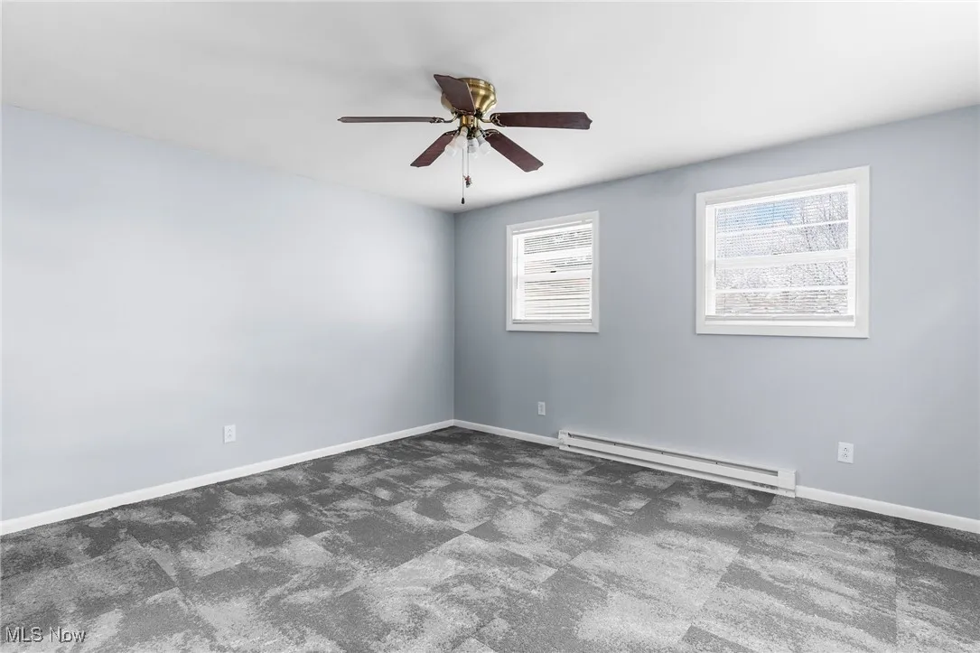Unfurnished room with baseboards, carpet flooring, a ceiling fan, and a baseboard radiator