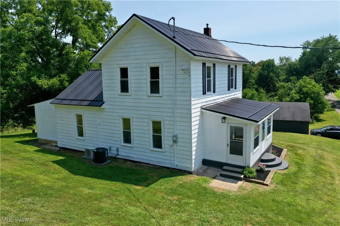 Back of house featuring a metal roof, a yard, entry steps, and a chimney