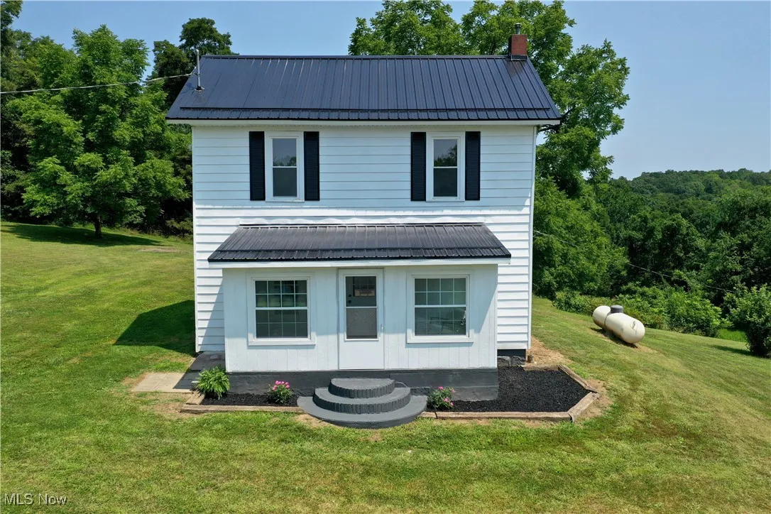 View of front of property featuring a metal roof, a front yard, a chimney, and an outdoor structure