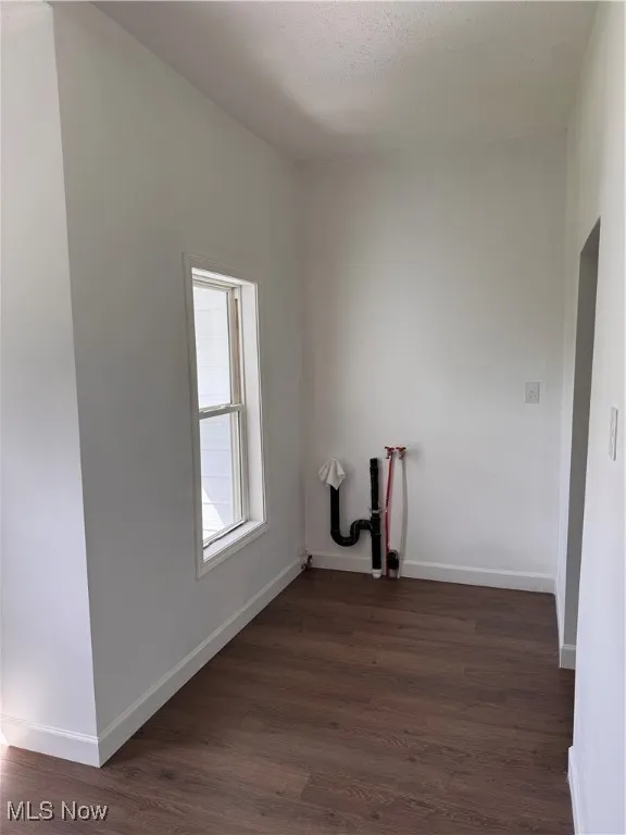 Laundry room with dark wood finished floors and baseboards
