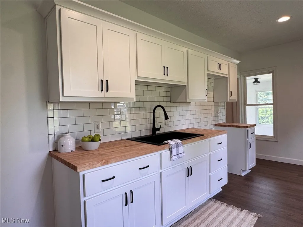 Kitchen with butcher block counters, tasteful backsplash, white cabinetry, recessed lighting, and a textured ceiling