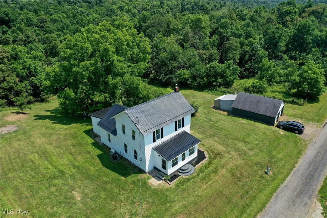 Aerial view of property and surrounding area with a heavily wooded area