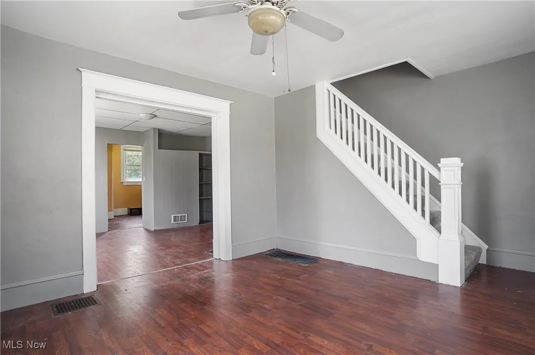 Unfurnished living room featuring wood finished floors and stairway