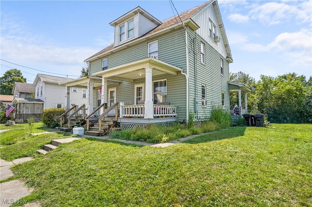 American foursquare style home featuring a front yard, a porch, and board and batten siding