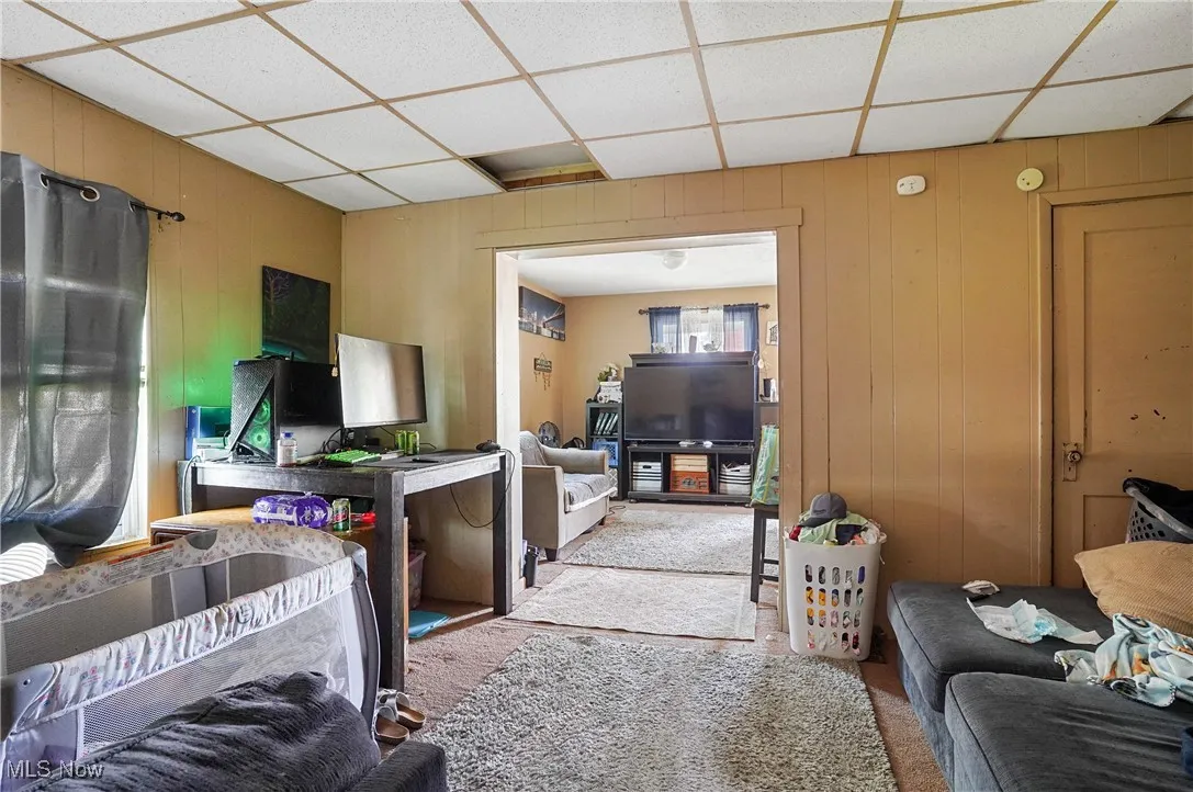 Living area featuring wood walls and a drop ceiling