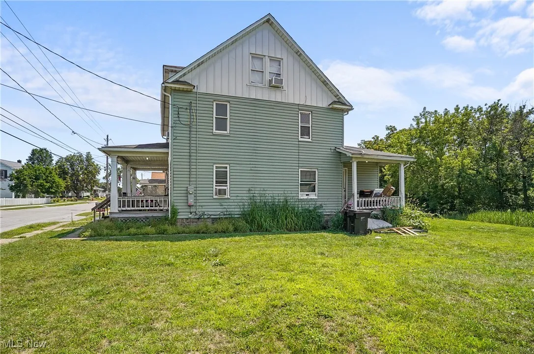 View of side of property featuring a porch, board and batten siding, and a lawn