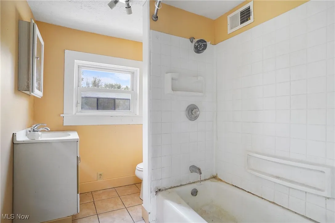 Bathroom featuring tile patterned floors, vanity, and washtub / shower combination