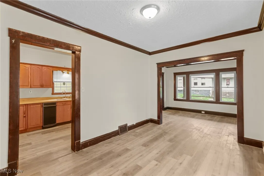 Spare room with a textured ceiling, ornamental molding, and light wood-style floors