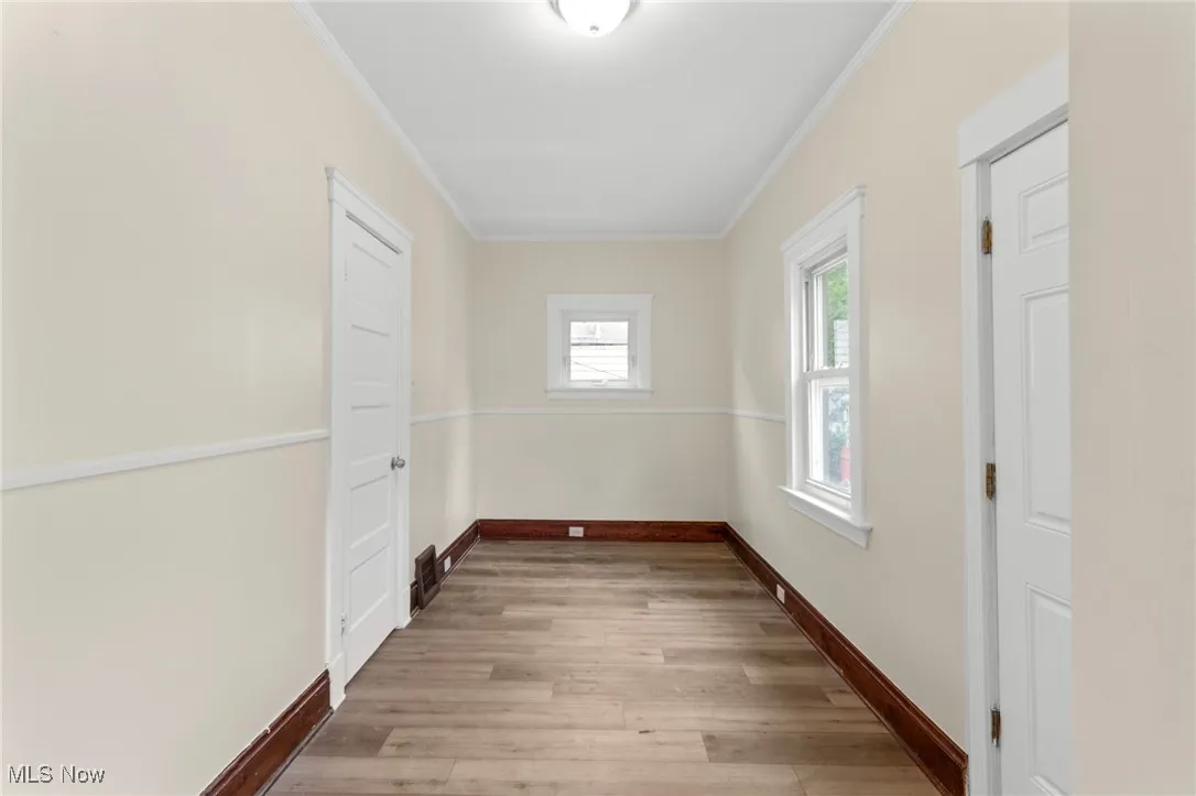 Hall with wood finished floors and ornamental molding