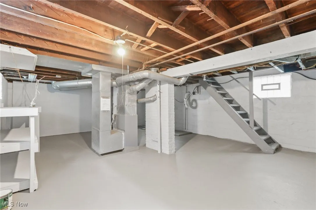 Basement featuring stairway and heating unit