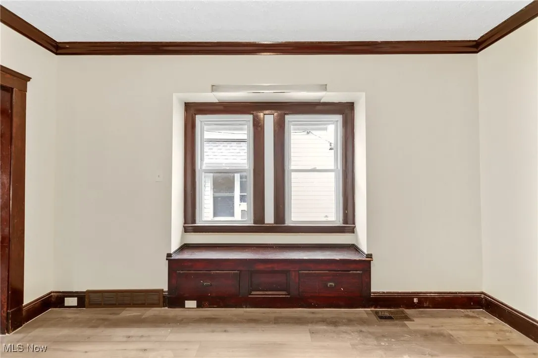 Spare room with ornamental molding and light wood finished floors