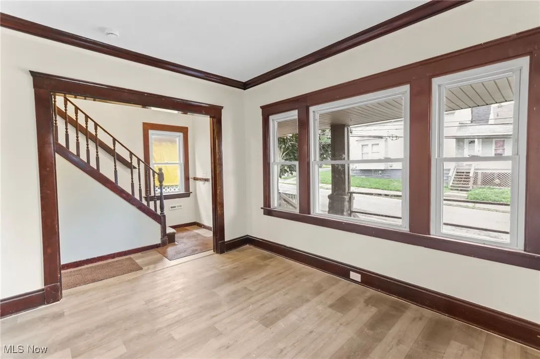 Entryway with crown molding, light wood-type flooring, and stairway