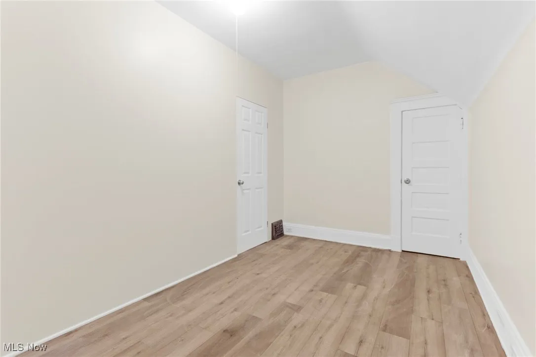 Bonus room with light wood-style flooring and vaulted ceiling