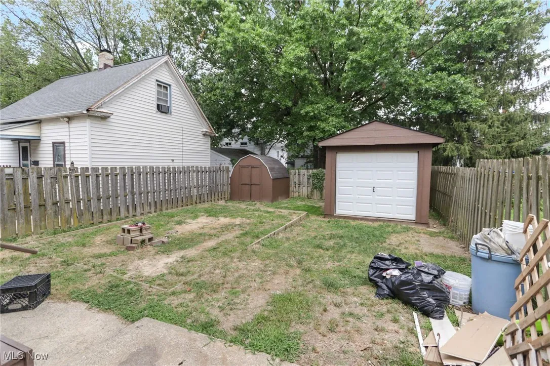 Fenced backyard with a storage unit and view of scattered trees