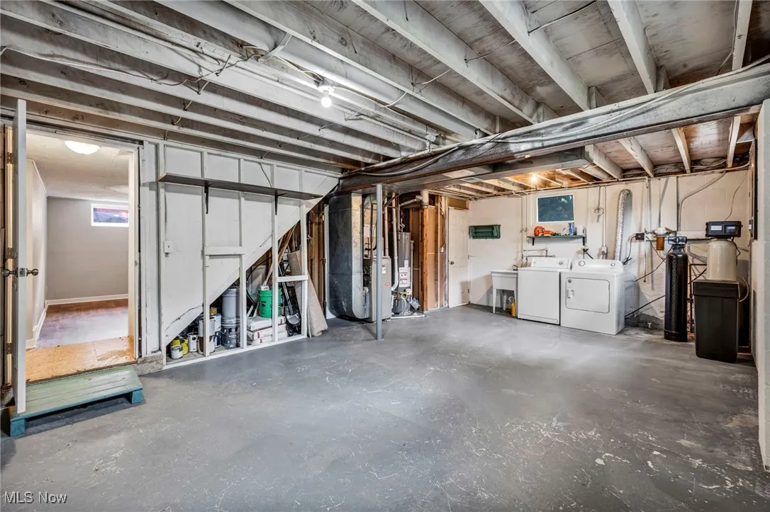 Basement with washer and clothes dryer, a water softener system, and water heater