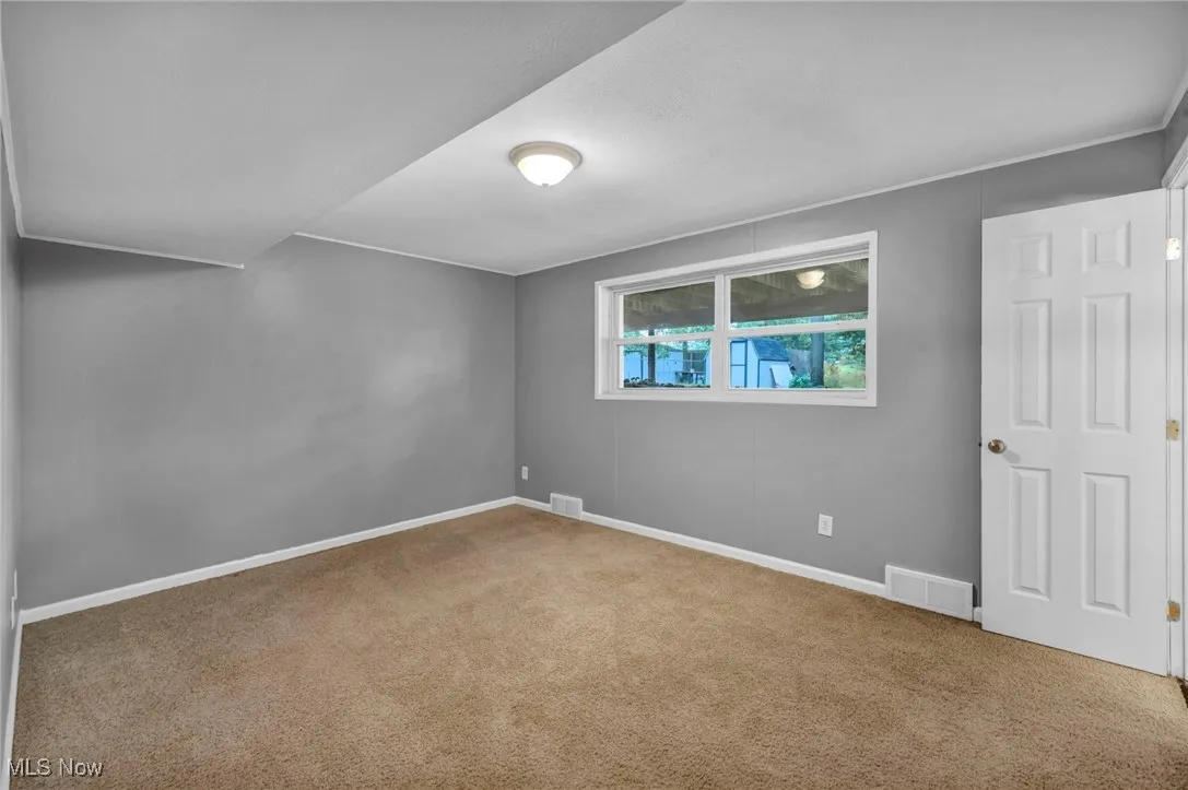 Spare room featuring carpet flooring and baseboards
