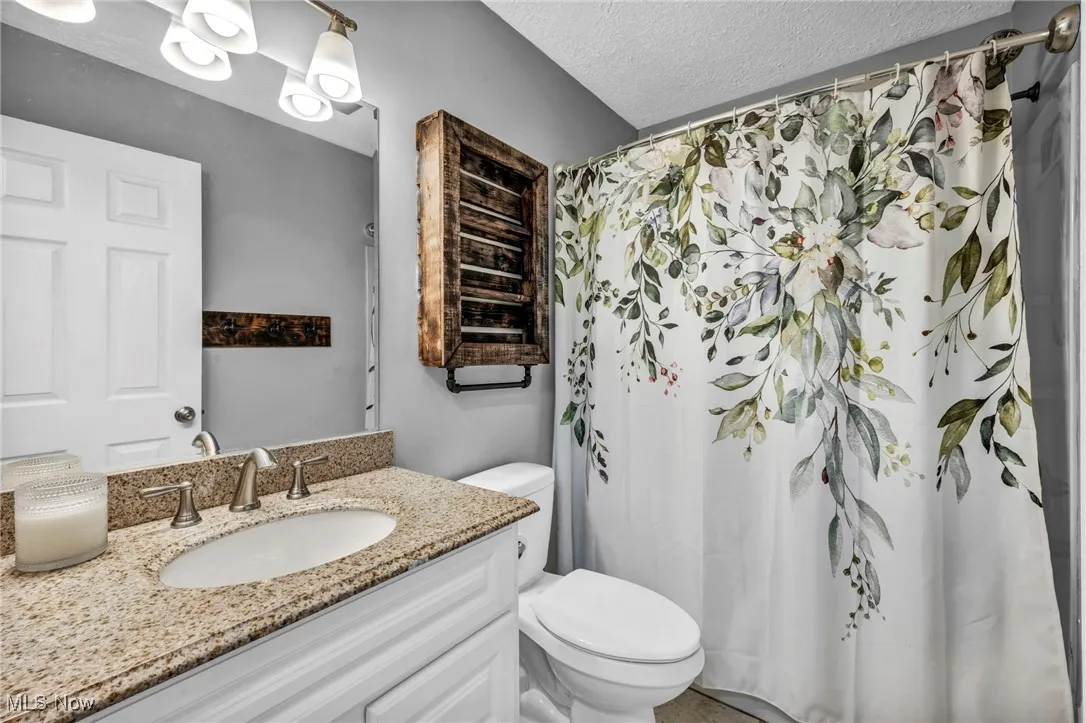 Bathroom featuring a textured ceiling, vanity, and a shower with shower curtain