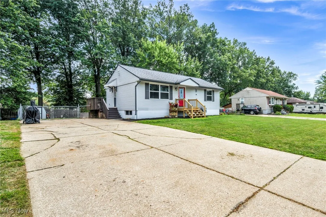 View of front of home with driveway, a shingled roof, and view of scattered trees