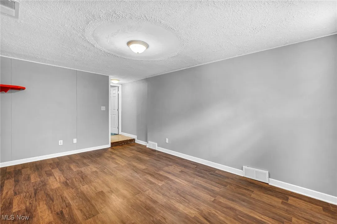Unfurnished room with a textured ceiling and wood finished floors