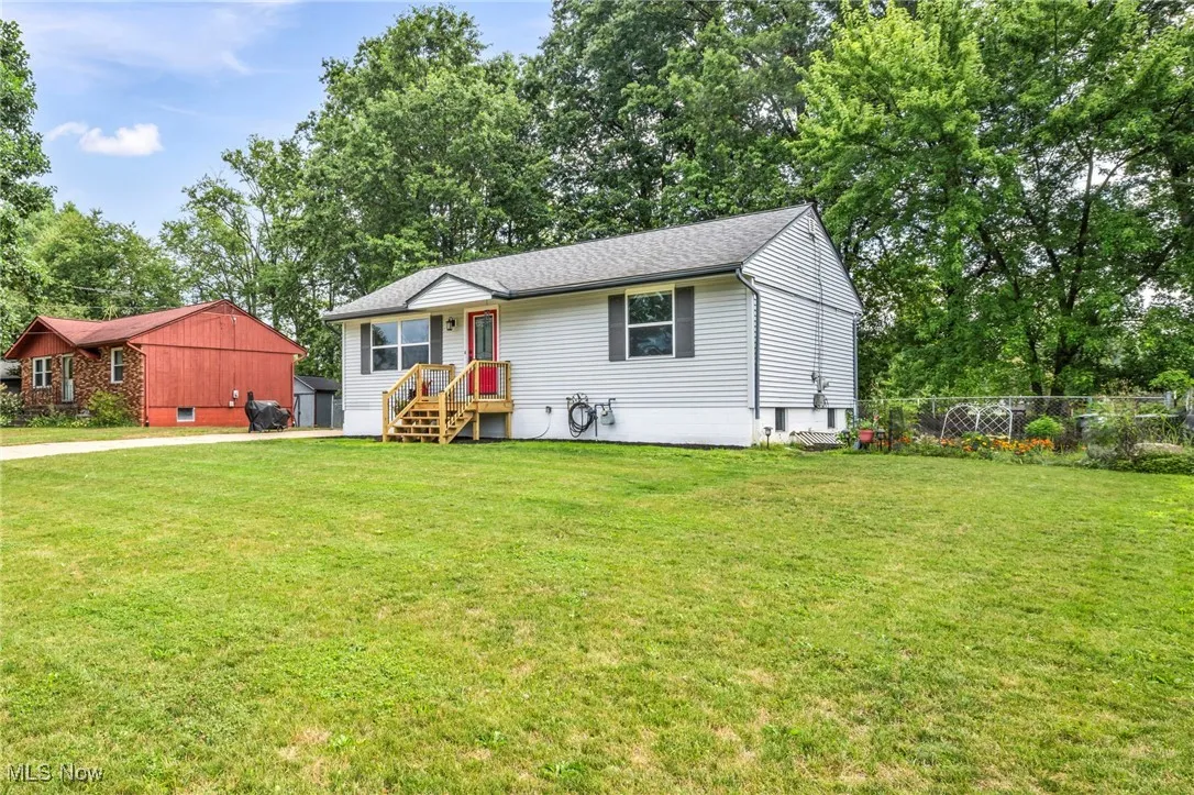 View of front of property with view of wooded area, roof with shingles, and a storage shed