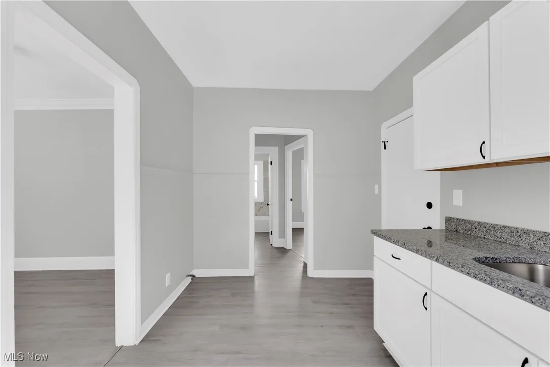 Kitchen featuring stone counters, white cabinets, and light wood finished floors