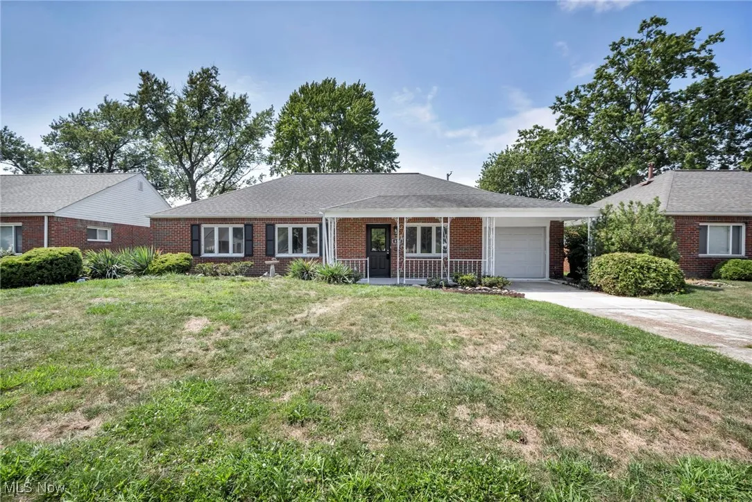 Ranch-style house featuring brick siding, an attached garage, concrete driveway, and a front yard