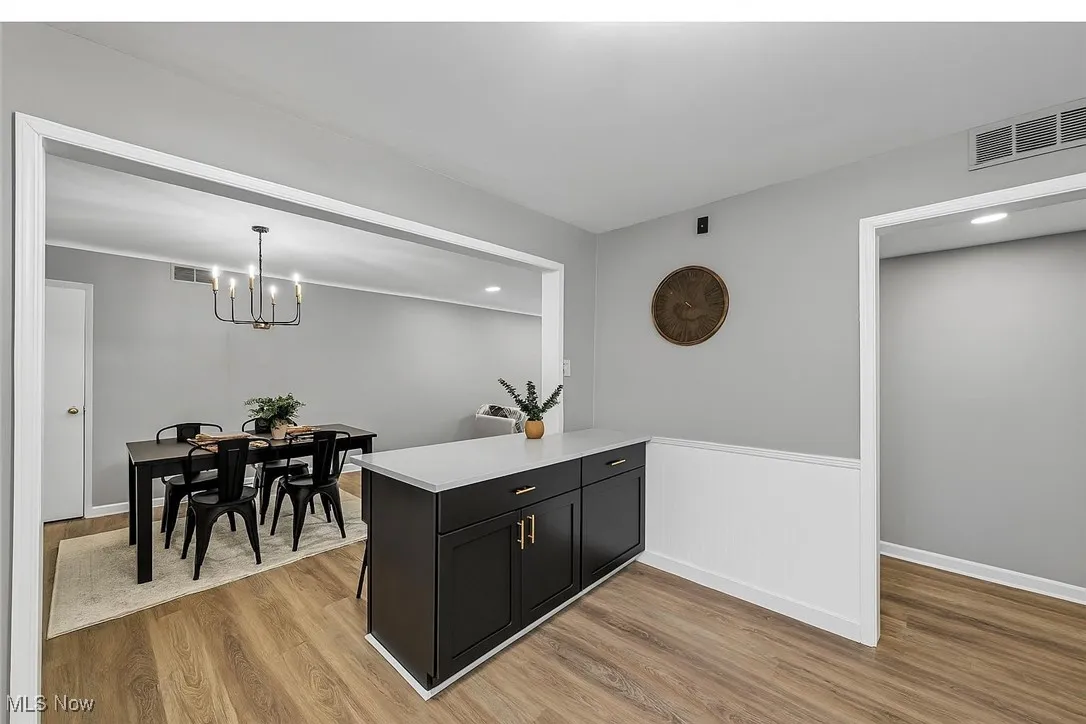 Kitchen with light wood-style flooring, a peninsula, light countertops, dark cabinetry, and recessed lighting