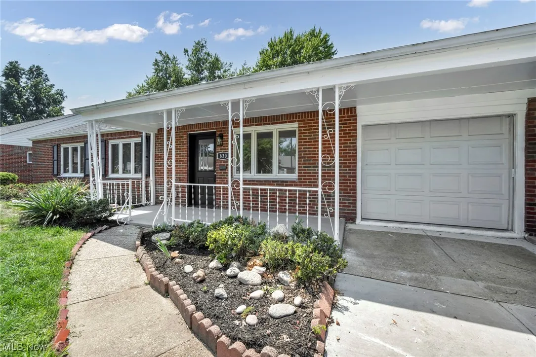 View of front of house with a porch, a garage, brick siding, and driveway
