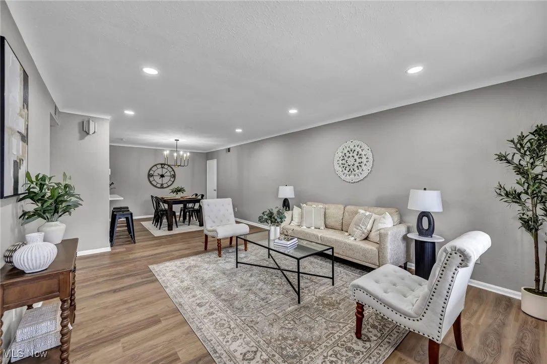 Living room featuring wood finished floors, a chandelier, recessed lighting, and ornamental molding