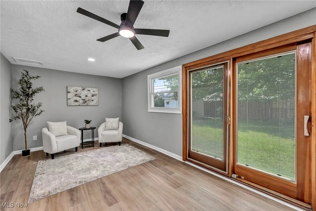 Sitting room with a textured ceiling, light wood finished floors, and a ceiling fan