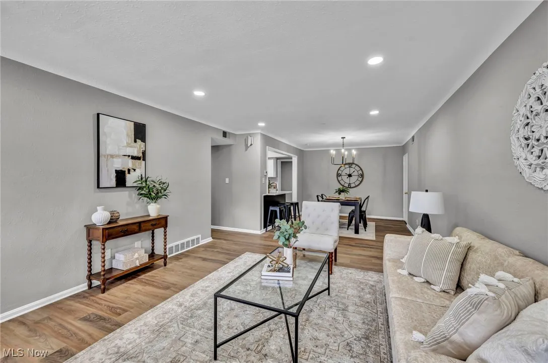 Living area with wood finished floors, recessed lighting, a chandelier, and crown molding