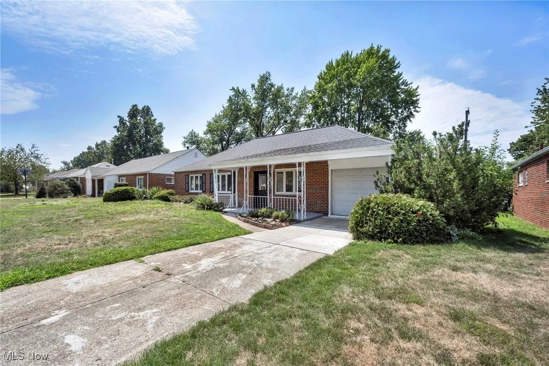 Ranch-style home with covered porch, an attached garage, a front lawn, brick siding, and driveway