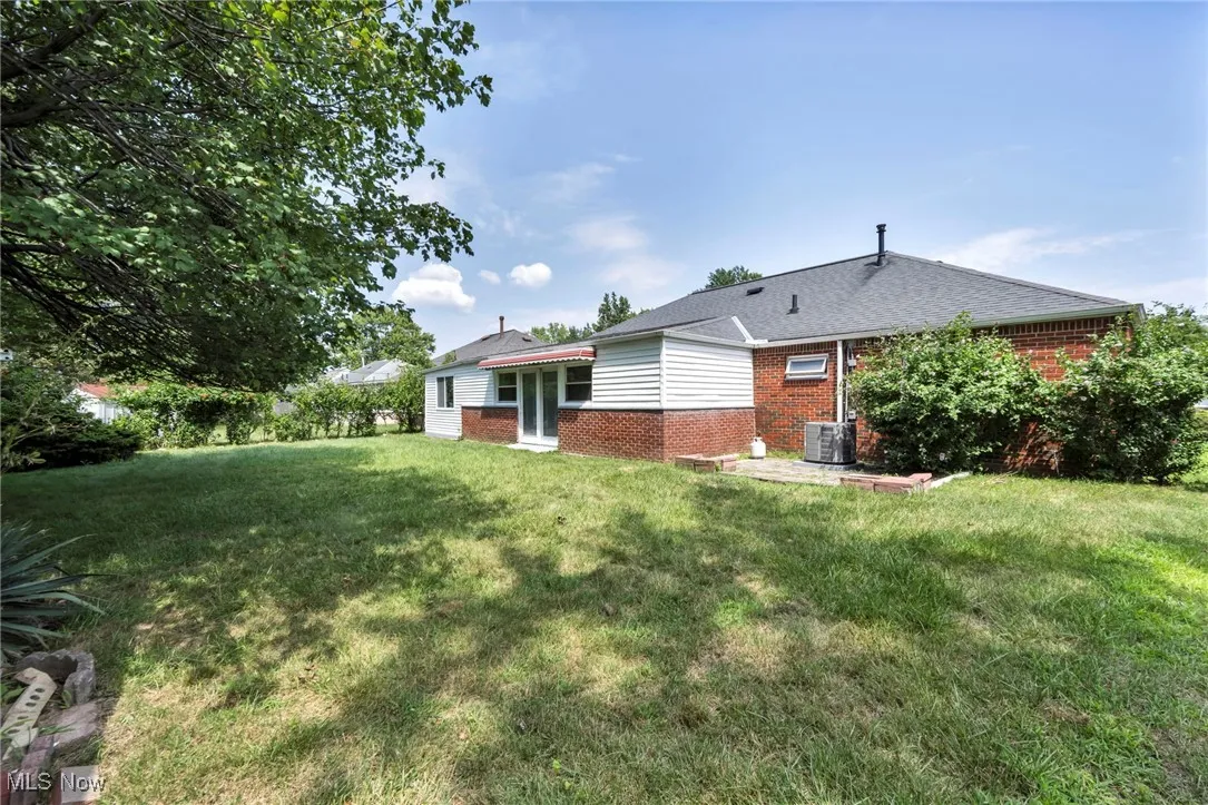 Back of property with brick siding and a yard