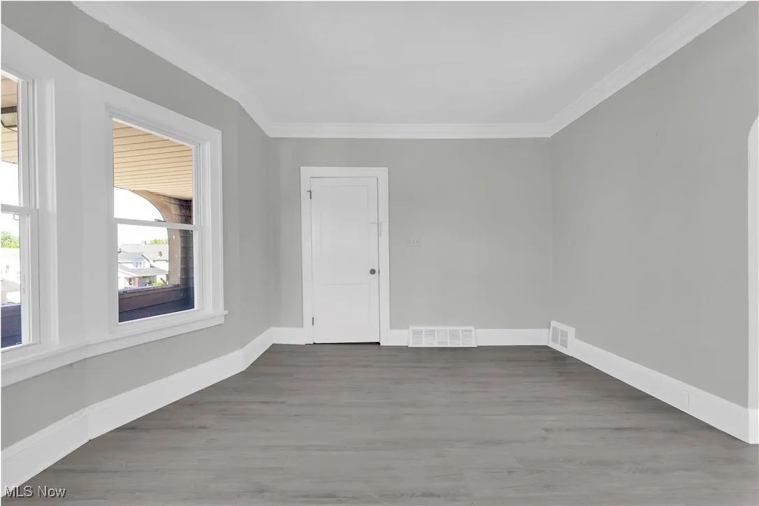 Unfurnished room featuring wood finished floors and crown molding