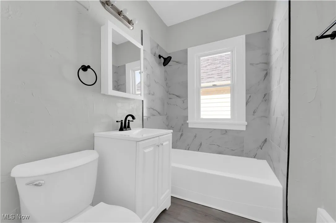 Full bath with vanity, shower / bathtub combination, and wood finished floors