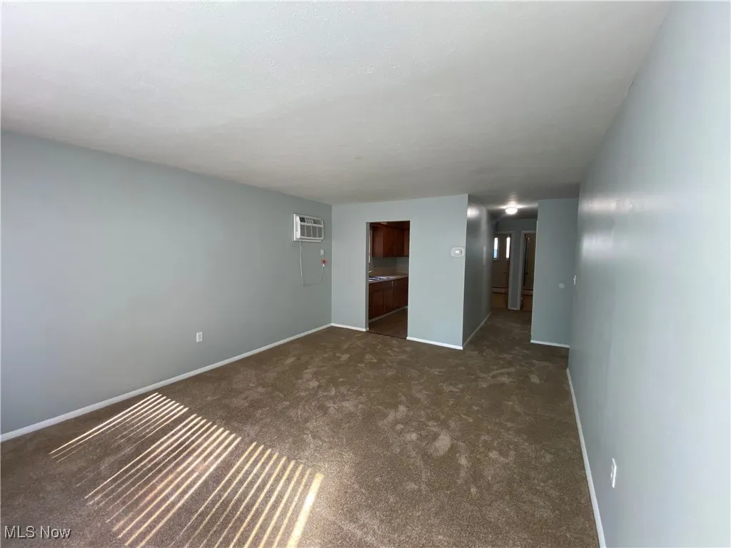 Spare room with dark carpet and a wall unit AC