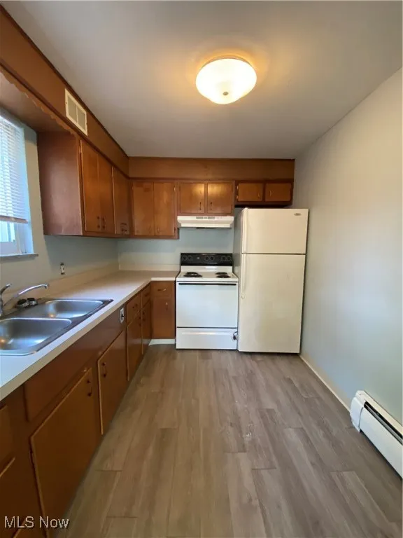 Kitchen featuring refrigerator, a baseboard heating unit, white range with electric cooktop, wood finished floors, and light countertops