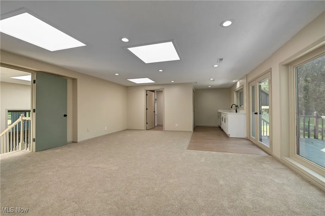 Unfurnished room with light carpet, recessed lighting, and a skylight