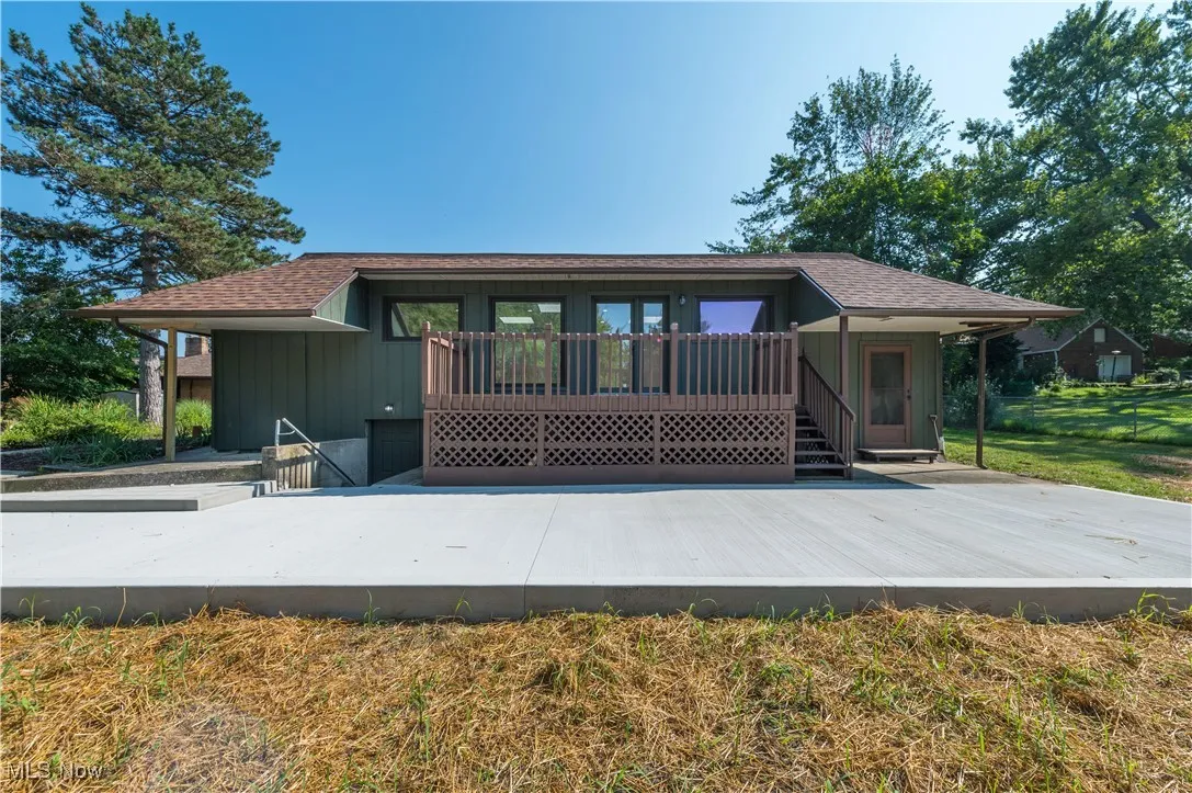 Rear view of property featuring a shingled roof and a wooden deck