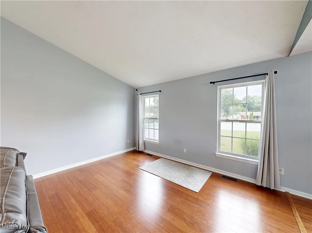 Unfurnished room with vaulted ceiling and wood finished floors