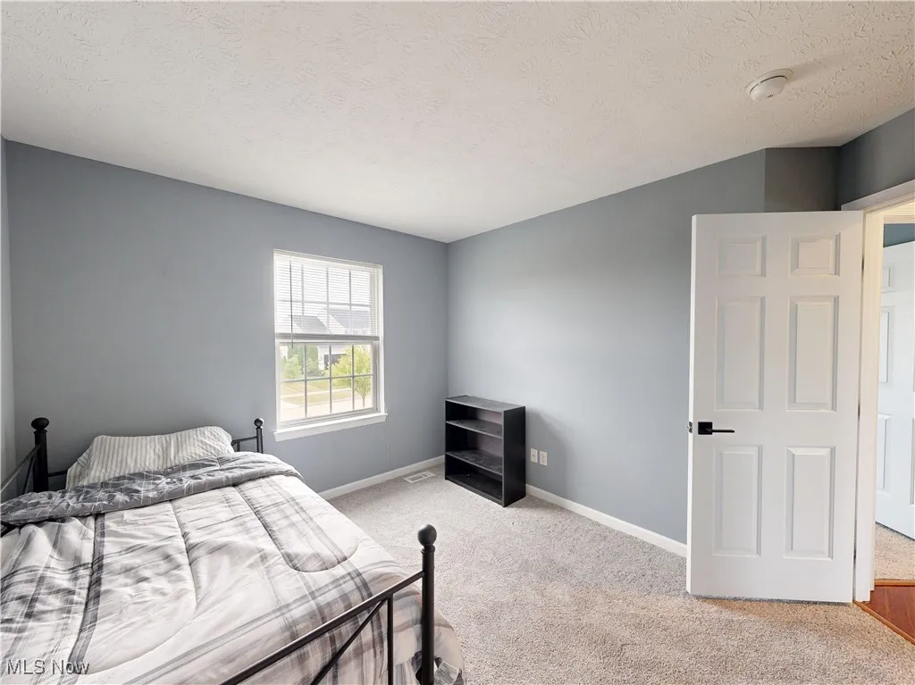 Bedroom featuring a textured ceiling and light carpet