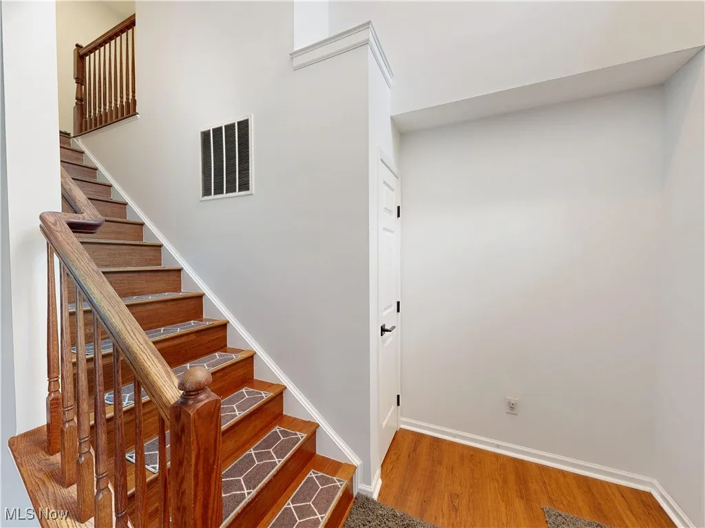 Stairway with wood finished floors and baseboards