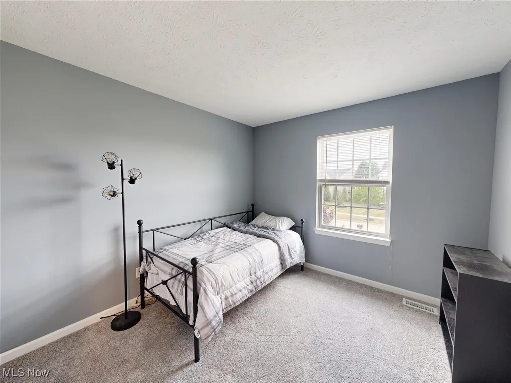 Carpeted bedroom featuring baseboards and a textured ceiling