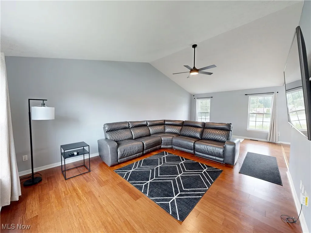 Living room featuring vaulted ceiling, wood finished floors, and a ceiling fan